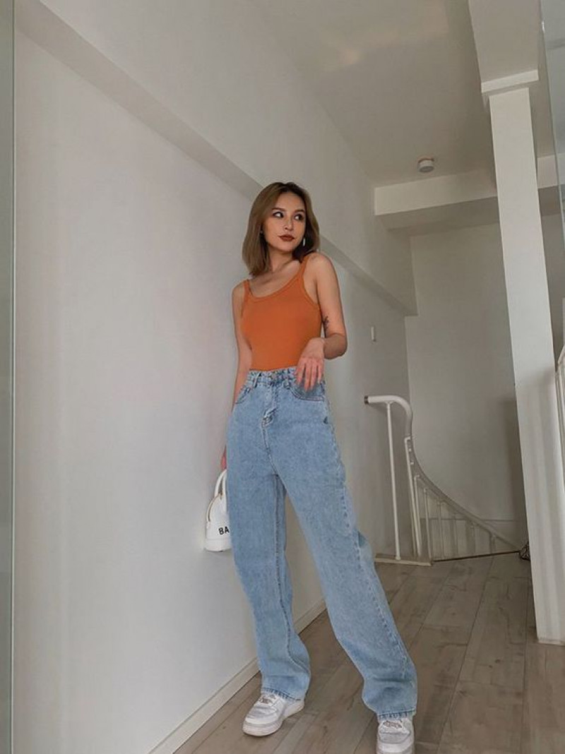 high waisted baggy jean, wide-leg jeans, high-rise, light blue casual trouser, orange top, white trainer, white sneaker, mom jeans